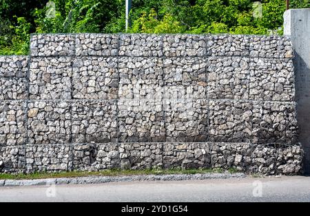 Schutzzaun oder Mauer aus Gabionen mit Steinen Stockfoto