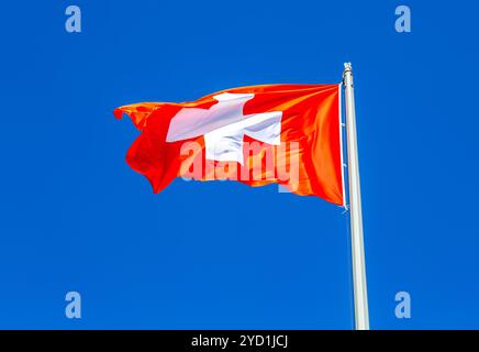 Die Flagge der Schweiz, die im Wind gegen den Himmel fliegt Stockfoto