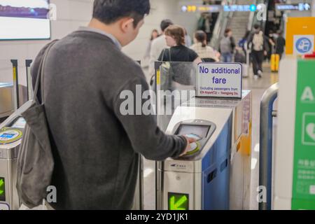 Der Mann steht vor einer Maschine, die keine zusätzlichen Fahrpreise sagt. Er schaut auf die Maschine Stockfoto