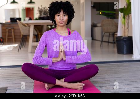 Frau, die zu Hause auf Yogamatte meditiert, inneren Frieden findet Stockfoto