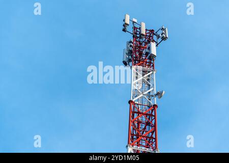 Nahaufnahme eines rot-weißen Telekommunikationsturms vor einem klaren blauen Himmel Stockfoto