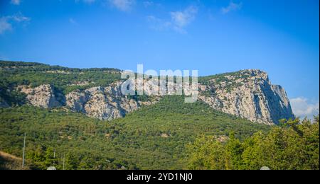 Russische Berge. Krim. Sommer Berge Hintergrund. Wald und Berge in der Sonne vor dem Hintergrund eines bewölkten Himmels darüber Stockfoto