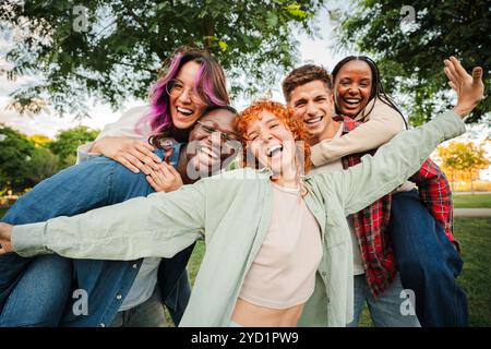 Gruppe fröhlicher junger Freunde, die sich im Freien amüsieren, gemeinsam in einem Park umarmen und lachen. Energiegeladene, sorglose und multirassische Menschen genießen einen lebendigen und spielerischen Moment der Freundschaft. Hochwertige Fotos Stockfoto