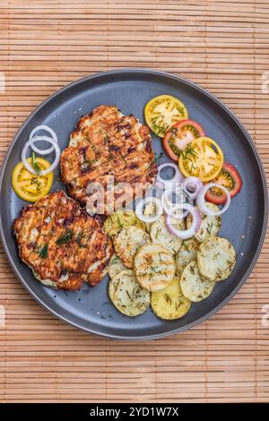 Gehacktes Hähnchenkotelett mit gegrilltem Gemüse liegt auf einem Teller. Gegrilltes Geflügel und Gemüse. Wunderschönes Essen. Speiseplan. Stockfoto
