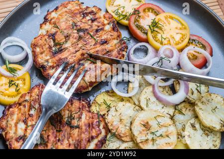 Gehacktes Hähnchenkotelett mit gegrilltem Gemüse liegt auf einem Teller. Gegrilltes Geflügel und Gemüse. Wunderschönes Essen. Speiseplan. Stockfoto