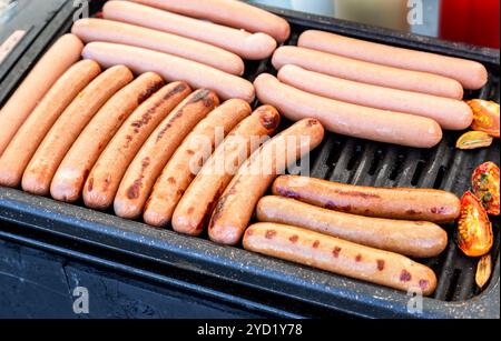 Würstchen auf einem Metallgitter, die über heißen Kohlen grillen Stockfoto