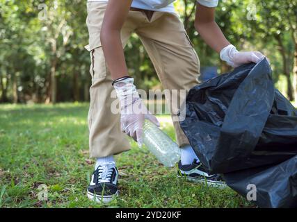 Ein Junge von engagierten Freiwilligen nimmt an einer Umweltreinigungsaktion in einem Park Teil. Der Junge trägt Handschuhe und hält große schwarze Taschen. Boy Col Stockfoto