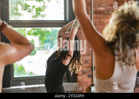 Eine spirituelle Dame wird in einem Fitnessraum gesehen, während sie den Menschen bei 108 Runden surya namaskar Sonnengrüße beim Stehen Asana-Posen beibringt. Stockfoto