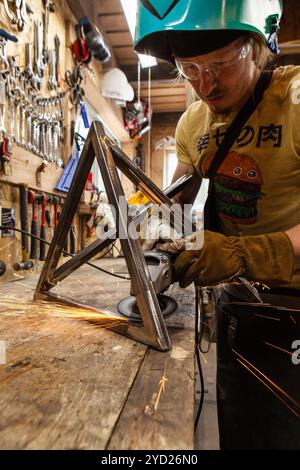 Schmied mit Winkelschleifer am Projekt Stockfoto