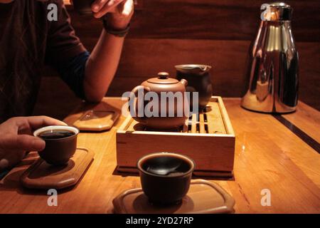 3 Personen probieren und trinken sehr dunklen pu-erh Tee in kleinen Probierbecher Stockfoto