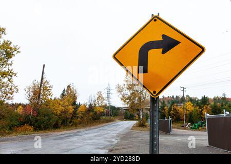 Biegen Sie rechts ein gelbes Straßenschild ab, das verbogen, gebeult, gerissen und rostig ist Stockfoto