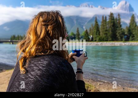 Lady trinkt ihren Kaffee am Fluss Canmore BC Stockfoto