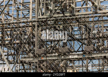 Nahaufnahme und selektiven Fokus auf der Außenseite Metall Zaun einer Unterstation mit hoher Spannung Elemente im Hintergrund Stockfoto