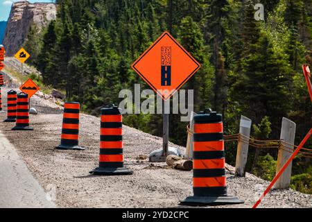 Gepflasterte Fläche endet vor orange unterzeichnen, vorübergehender Zustand schildern Fässer, Warnzeichen, die auf der rechten Straßenseite, im Bau Asphalt Stockfoto