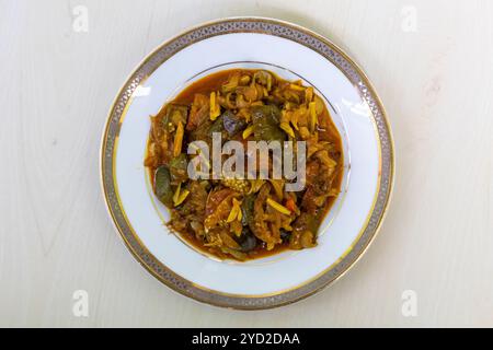 Nona ilish Bhuna Curry mit Brinjal auf einem weißen Teller. Salted Hilsa Fisch Vuna ist ein beliebtes bangladeschisches Gericht, das aus getrocknetem Ilish-Fisch zubereitet wird. Draufsicht. Stockfoto