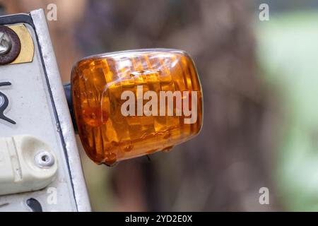 Nahaufnahme eines orangefarbenen Motorradblinkers rechts vor einem unscharfen Hintergrund. Stockfoto