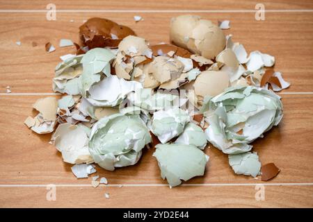 Zerbrochene Eierschalen sind über die Holzoberfläche verstreut. Recycling von Küchenabfällen, einschließlich zerkleinerter Eierschalen, für Kompost und Gartenzwecke. Stockfoto