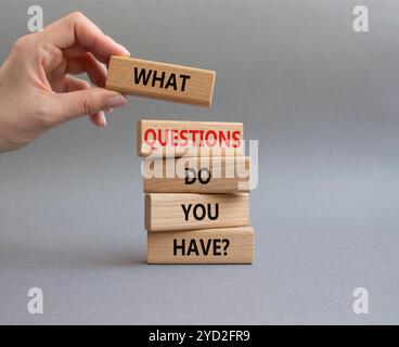 Symbol „Fragen“. Holzblöcke mit Worten Was haben Sie? Schöner grauer Hintergrund. Geschäftsmann Hand. Unternehmen und welche Fragen haben Sie Stockfoto