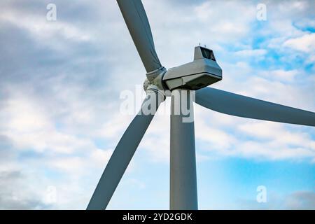 Niedriger Winkel und Nahaufnahme auf dem Maschinenhaus, Abdeckung des Gehäuses der erzeugenden Komponenten einer Windenergieanlage mit drei Rotorblättern gegen einen gebrochenen Wolkenhimmel Stockfoto