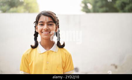 Glückliche indische Grundschüler, die am Schreibtisch im Klassenzimmer sitzen und in Notizbuch mit Bleistift schreiben, Prüfung und Test, weibliche Lehrerin Stockfoto