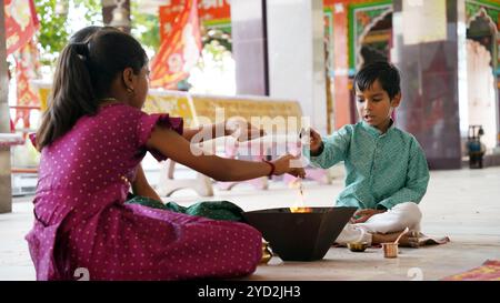 Eine indische Familie in traditioneller Kleidung führt eine Yagya oder Havan aus, die von einem Priester geleitet wird, um die Energien in ihrem Haus auszugleichen. Dieser heilige pooja ist für Harmonie Stockfoto