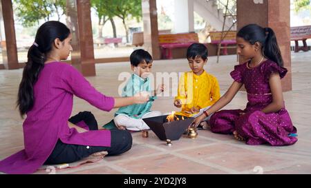 Eine indische Familie in traditioneller Kleidung führt eine Yagya oder Havan aus, die von einem Priester geleitet wird, um die Energien in ihrem Haus auszugleichen. Dieser heilige pooja ist für Harmonie Stockfoto