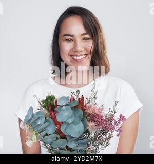 Studio, Blumenstrauß und Blumen mit asiatischer Frau im Porträt, Überraschung und Geschenk der Pflanze zum Valentinstag. Geschenk, weibliche Person und Lächeln mit Blumen Stockfoto