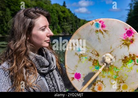 Junge Frau, die heilige Trommel und Pelzstock spielt Stockfoto