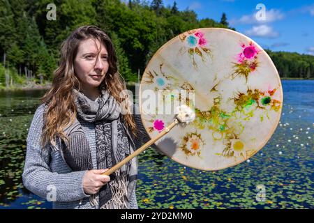 Junge Frau, die heilige Trommel und Pelzstock spielt Stockfoto