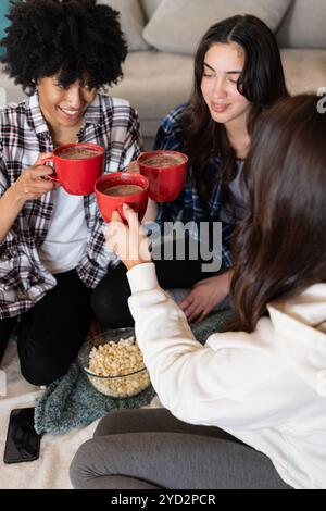 Weihnachten, gemeinsame Freundinnen genießen heiße Schokolade und Popcorn zu Hause Stockfoto
