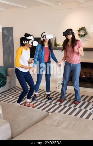 Gemeinsame Freundinnen, die während der Weihnachtsfeier Virtual-Reality-Spiele zu Hause genießen Stockfoto