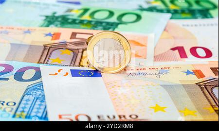 Geldhintergrund aus der Währung von Euro-Banknoten mit einer Euro-Münze Stockfoto