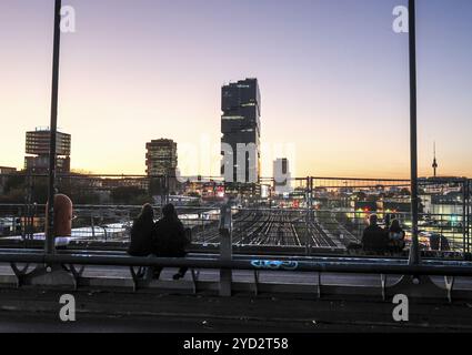 Entspannen Sie bei Sonnenuntergang auf der Modersohn-Brücke, Blick auf Eisenbahngleise, Züge und den 140 Meter hohen Amazonas-Büroturm Edge East Side, Berlin, 23,1 Stockfoto