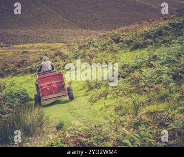 Ein Hill Farmer auf Einem Quad mit Anhänger im ländlichen Schottland Stockfoto