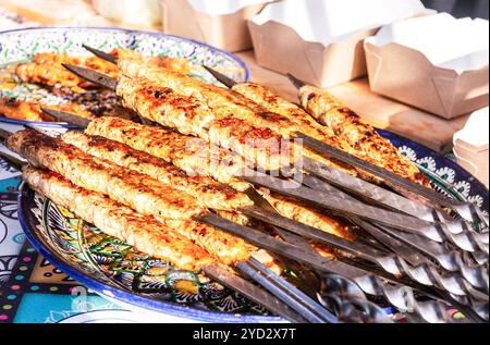 Gegrillter Kebab, der auf Metallspießen kocht Stockfoto