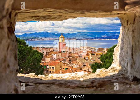 Der Kirchturm des Dorfes Saint Tropez und die alten Dächer blicken durch ein Steinfenster Stockfoto