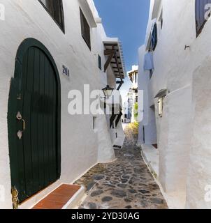 Binibeca Vell, Spanien, 24. Januar 2024: Eine enge Gasse führt durch ein Labyrinth von weiß getünchten Gebäuden im Zentrum von Binibeca Vell, Europa Stockfoto