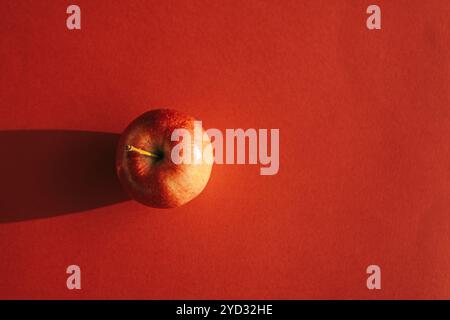 Roter Apfel bildet einen Schatten vor rotem Hintergrund Stockfoto