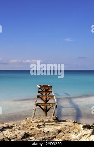 Ein altes Dock führt hinaus in das türkisfarbene Wasser des SES Illetes Beach im Norden von Formentera Stockfoto