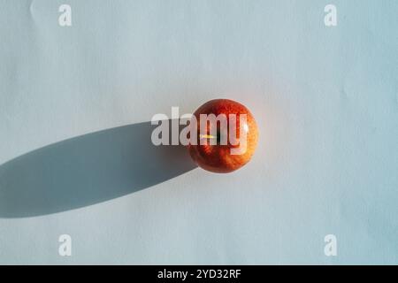 Roter Apfel, der einen Schatten vor weißem Hintergrund bildet Stockfoto