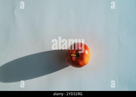Roter Apfel, der einen Schatten vor weißem Hintergrund bildet Stockfoto