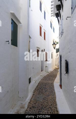 Binibeca Vell, Spanien, 24. Januar 2024: Eine enge Gasse führt durch ein Labyrinth von weiß getünchten Gebäuden im Zentrum von Binibeca Vell, Europa Stockfoto