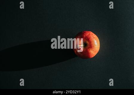 Roter Apfel, der einen Schatten vor schwarzer Umrandung bildet Stockfoto