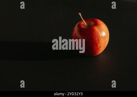 Roter Apfel, der einen Schatten vor schwarzer Umrandung bildet Stockfoto