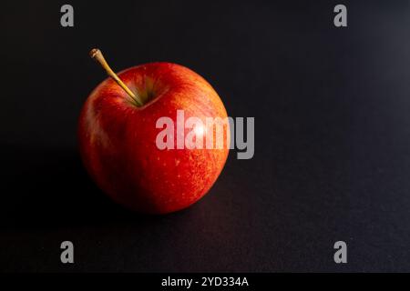Roter Apfel, der einen Schatten vor schwarzer Umrandung bildet Stockfoto