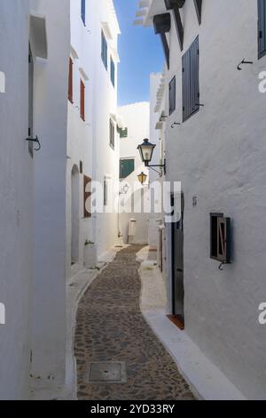 Binibeca Vell, Spanien, 24. Januar 2024: Eine enge Gasse führt durch ein Labyrinth von weiß getünchten Gebäuden im Zentrum von Binibeca Vell, Europa Stockfoto