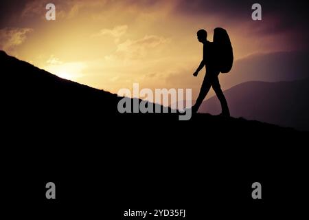 Retro Stil Design eines Silhouette jungen Mannes Wandern herauf einen steilen Hügel bei Sonnenuntergang Stockfoto