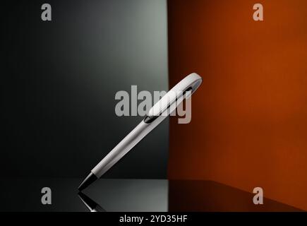 Weißes Stiftprodukt auf schwarzer glänzender Oberfläche mit zweifarbigem Hintergrund. Diagonal positioniert für eine dynamische Perspektive. Stockfoto