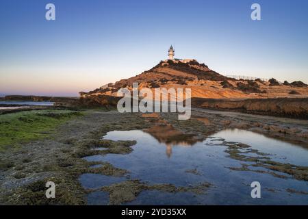 Blick auf den Leuchtturm Cabo de la Huerta bei Sonnenaufgang mit Reflexionen in Gezeitenbecken im Vordergrund Stockfoto