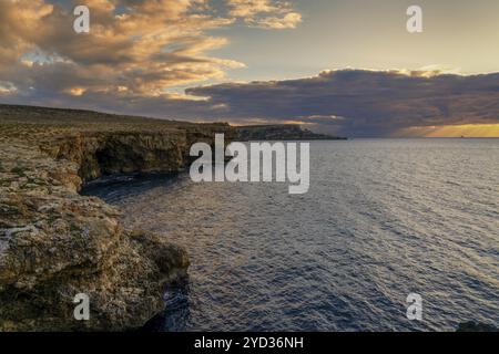 Eine Meereslandschaft bei Sonnenuntergang in Malta mit den Popeye Cliffs und einem Blick auf das Meer in Anchor Bay Stockfoto